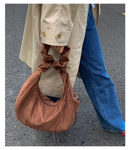 Detail of caramel brown suede handbag with trendy pleated scrunchie handle for street style