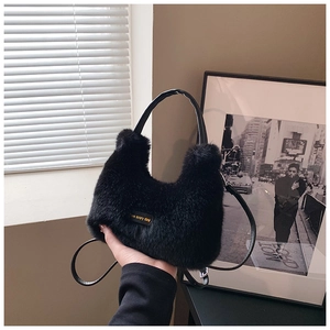 Detail of plush black faux fur handbag featuring leather handle and golden brand tag