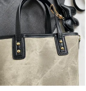 Detail of canvas tote bag featuring black leather trim and cute puppy charm accessory