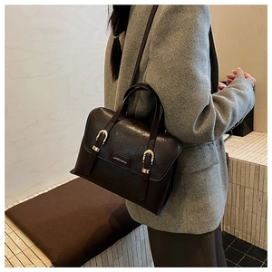 Macro shot of dark brown matte PU leather handbag with gold buckles and brand logo