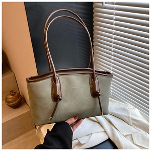 Detail of sage green tote bag with knotted brown handles and gold metal accents