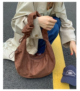 Detail view of large brown suede hobo bag with knot strap detail on a street setting