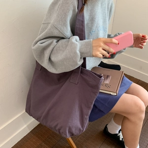 Close-up of a large purple canvas tote bag worn over the shoulder for daily commute