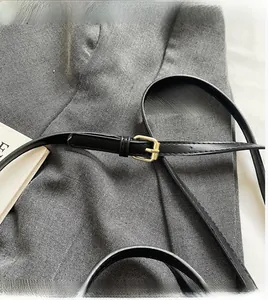 Detail of black adjustable leather shoulder strap with gold buckle on crossbody bag