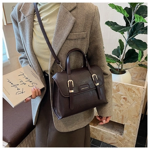 Detail of vintage brown leather handbag with gold buckle and adjustable shoulder strap