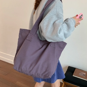 Detailed side view of a large purple canvas tote bag worn over the shoulder for daily use