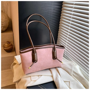 Detailed close-up of pink suede tote bag with brown handles and elegant knot accents