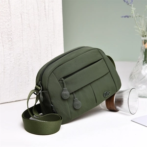 Detail view of military green nylon crossbody bag with multi-layer zipper compartments