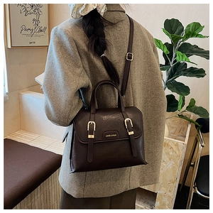 Detail of vintage dark brown faux leather texture and polished metal logo plaque on bag
