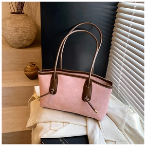 Detail of pink suede tote bag featuring brown leather straps and drawstring knot details