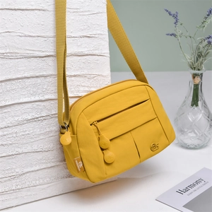 Detail view of yellow nylon crossbody bag featuring multi-layer zip compartments and metal logo