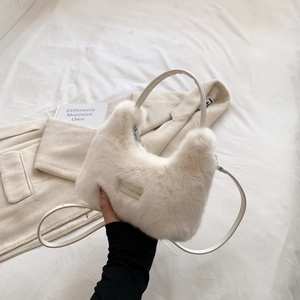 Detail of white faux fur handbag featuring love every day metal tag and leather strap