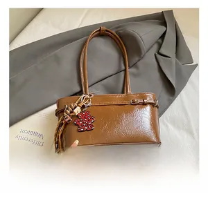 Detail of a brown oil-wax leather shoulder bag with a leopard heart bear charm