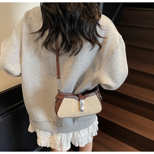 Dettaglio borsa a tracolla trapuntata beige con finiture in pelle marrone indossata dal modello