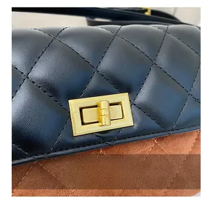 Close-up of golden rectangular turn-lock on quilted black leather and brown suede bag