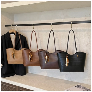Détail de grands sacs cabas aux bords ondulés et breloques en bois en quatre couleurs
