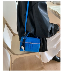 Petit sac bleu avec pendentif coeur en argent et bandoulière tressée sur un modèle