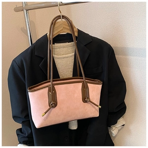 Close-up of pink frosted tote bag with brown leather trim on black suit jacket