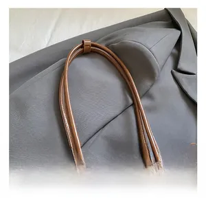 Close-up of caramel brown oily leather tote bag handles and metallic buckle details