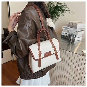 Close-up of vintage bicolor crossbody bag with metal buckles and leather brand patch