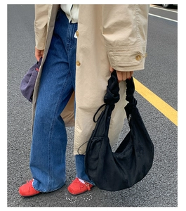 Detail of a black suede crescent bag with gathered handle and street style styling