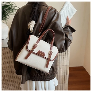 Detail view of a beige and brown vintage satchel bag with golden buckles and shoulder strap