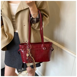 Detail of dark red patent leather tote with wrinkled texture and leopard print charm