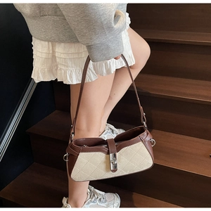 Dettaglio borsa a tracolla trapuntata beige con finiture in pelle marrone e fibbia in metallo