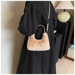 Detail view of light camel plush saddle bag with gold logo on black winter coat