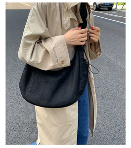 Street view of a large black suede hobo bag with minimalist design for daily commute