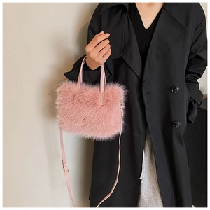 Pink faux fur handbag with leather handle styled on a long black coat backdrop