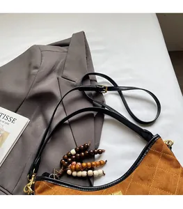 Detail of brown quilted suede underarm bag with adjustable strap and wooden bead charms
