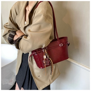 Detail of red glossy patent leather tote with leopard print tassel charm on shoulder strap
