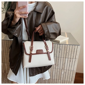 Close-up of cream PU leather messenger bag with brown straps and gold metal buckles