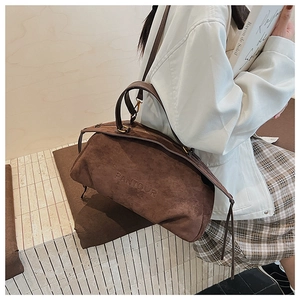 Detailed close-up of dark brown suede bag featuring embossed PANTOUR logo texture