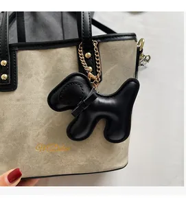 Detail of beige textured tote bag with golden logo and black puppy charm decoration