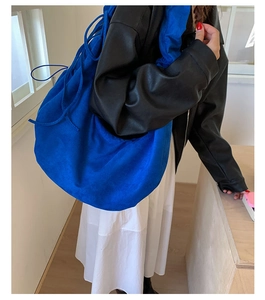 Detail of royal blue pleated crossbody bag showing soft texture and drawstring closure