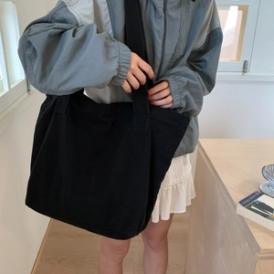Lifestyle shot of large black canvas tote bag carried by model in casual outfit