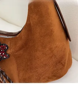 Gros plan sur sac en daim marron avec bandoulière rayée et breloque fleur léopard