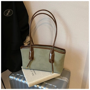 Close-up of green suede and brown leather tote bag with vintage embossed logo
