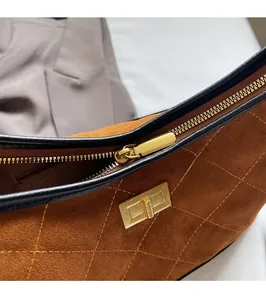 Detailed view of brown suede underarm bag with quilted stitching and gold zipper hardware