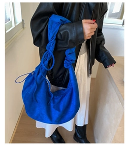 Detail of royal blue hobo bag with ruched strap and soft pleated suede texture
