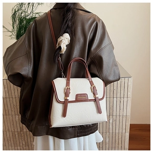 Detail of cream vintage messenger bag with brown straps and golden buckle on model