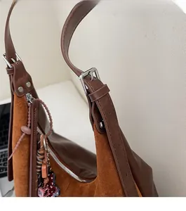Gros plan du sac en daim marron montrant la boucle en métal argenté et les détails du cuir
