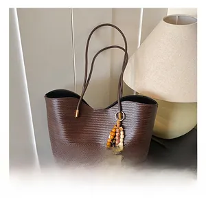 Détail d'un sac cabas tissé marron foncé avec un charme en perles de bois multicolores