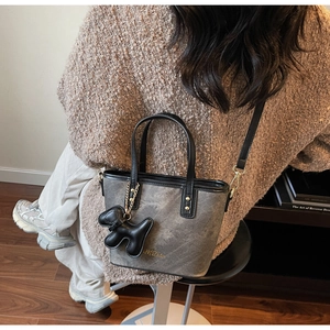 Detail of grey bucket bag with black leather trim and cute puppy charm on a shoulder strap