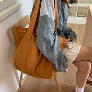 Detail of a large ginger canvas tote bag worn by a model in a natural lifestyle setting