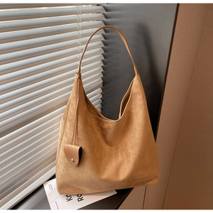 Close-up of caramel suede tote bag with heart charm detail and large interior space