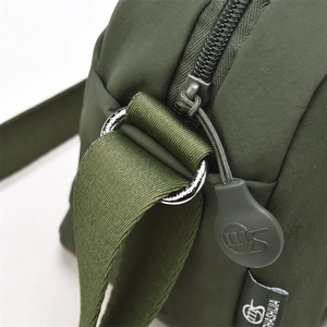 Macro shot of durable olive nylon fabric with metallic D-ring and brand logo detail