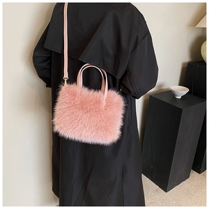 Close-up of pink faux fur handbag with leather handle worn with a black wool coat